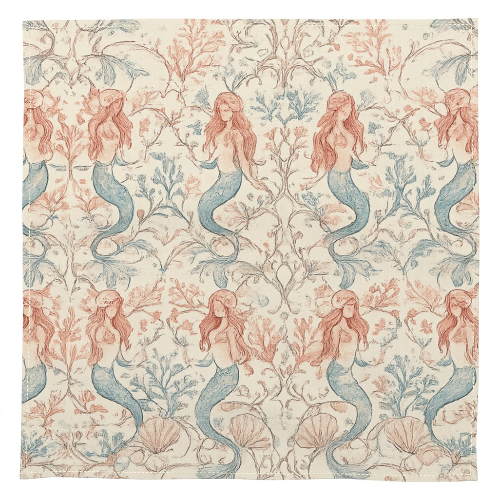 A square textile or fabric panel featuring a repeating mermaid and coral sea-plant pattern on a warm cream background. The mermaids have pink hair and blue tails, with coral in muted pink and blue-gray tones.
