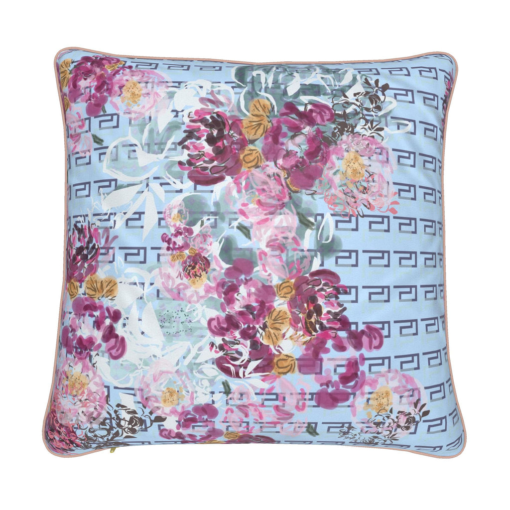 A square decorative throw pillow featuring a light blue background with a repeating dark gray Greek key pattern and a large watercolor-style floral print in pink, purple, and green, finished with a thin beige piped edge.