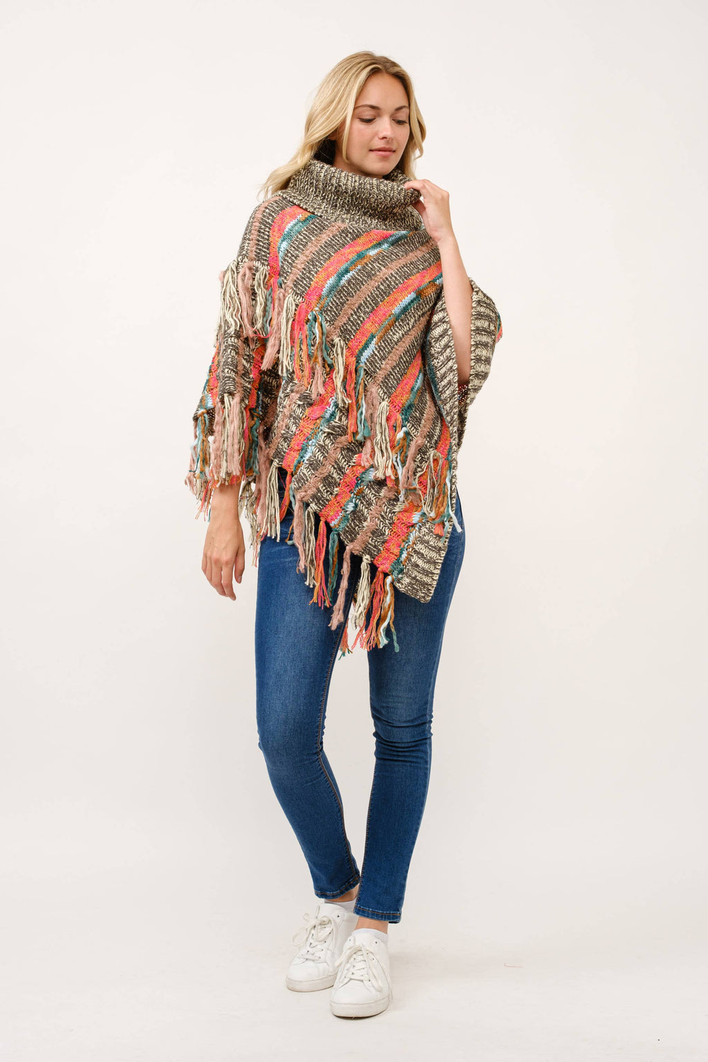 Woman wearing a patterned poncho with fringes on a white background