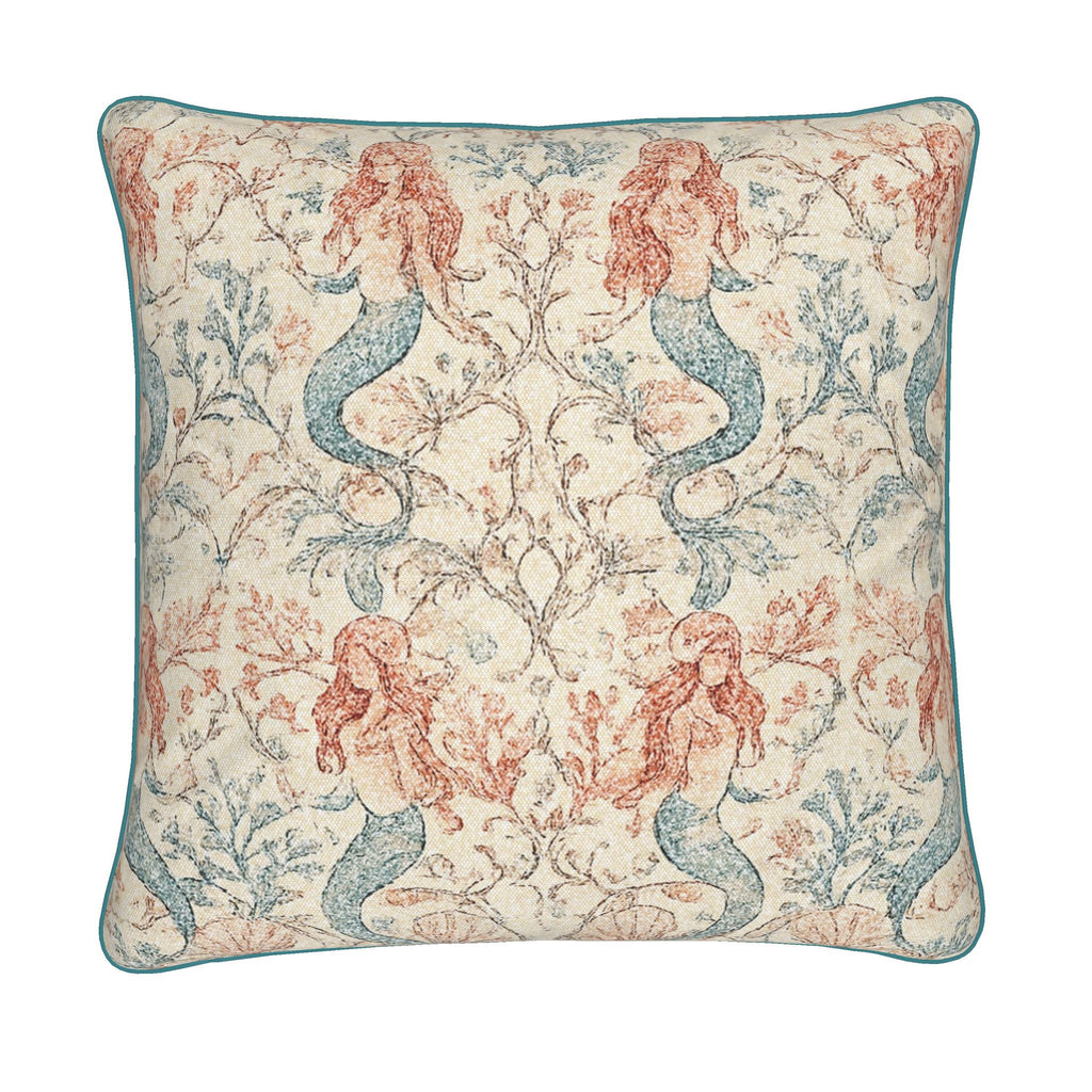 A square decorative throw pillow featuring a mermaid and coral botanical pattern in muted blue and terracotta on a cream background, finished with a teal piped edge.