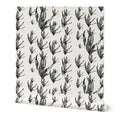 A roll of wallpaper featuring a repeating black botanical leaf pattern on a warm off-white background, shown standing upright with a slight perspective angle.