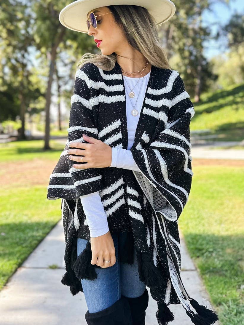 Woman wearing a black and white striped poncho in an outdoor setting