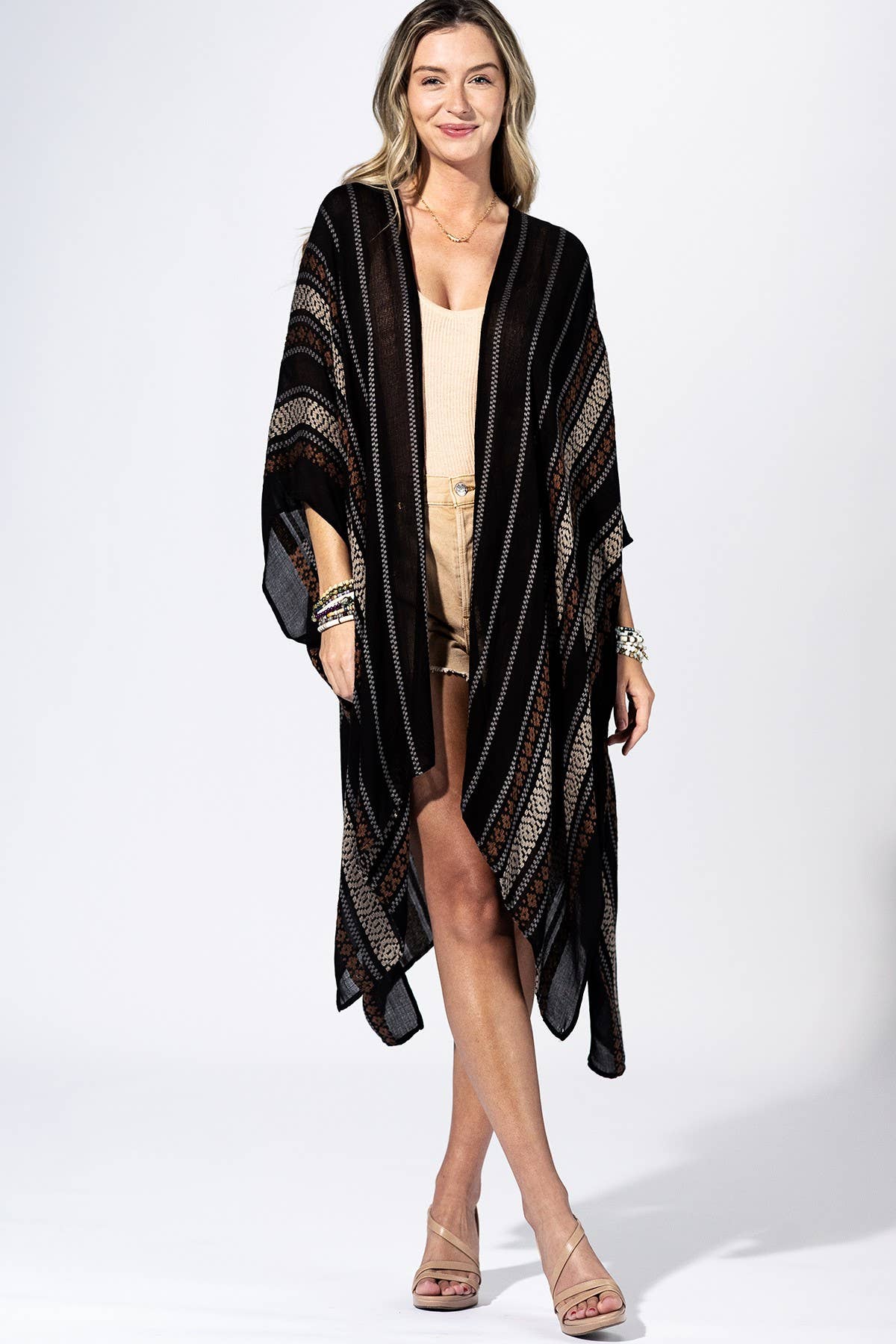 Woman wearing a black and gold patterned kimono over a beige outfit on a white background
